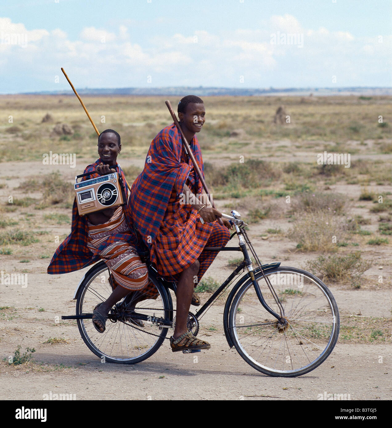 Tanzania, Arusha, Mto wa Mbu. Old and new. Dressed traditionally and carrying familiar wooden staff, two young men give hints that the lifestyle of younger Maasai generations is changing gradually in Tanzania. Stock Photo