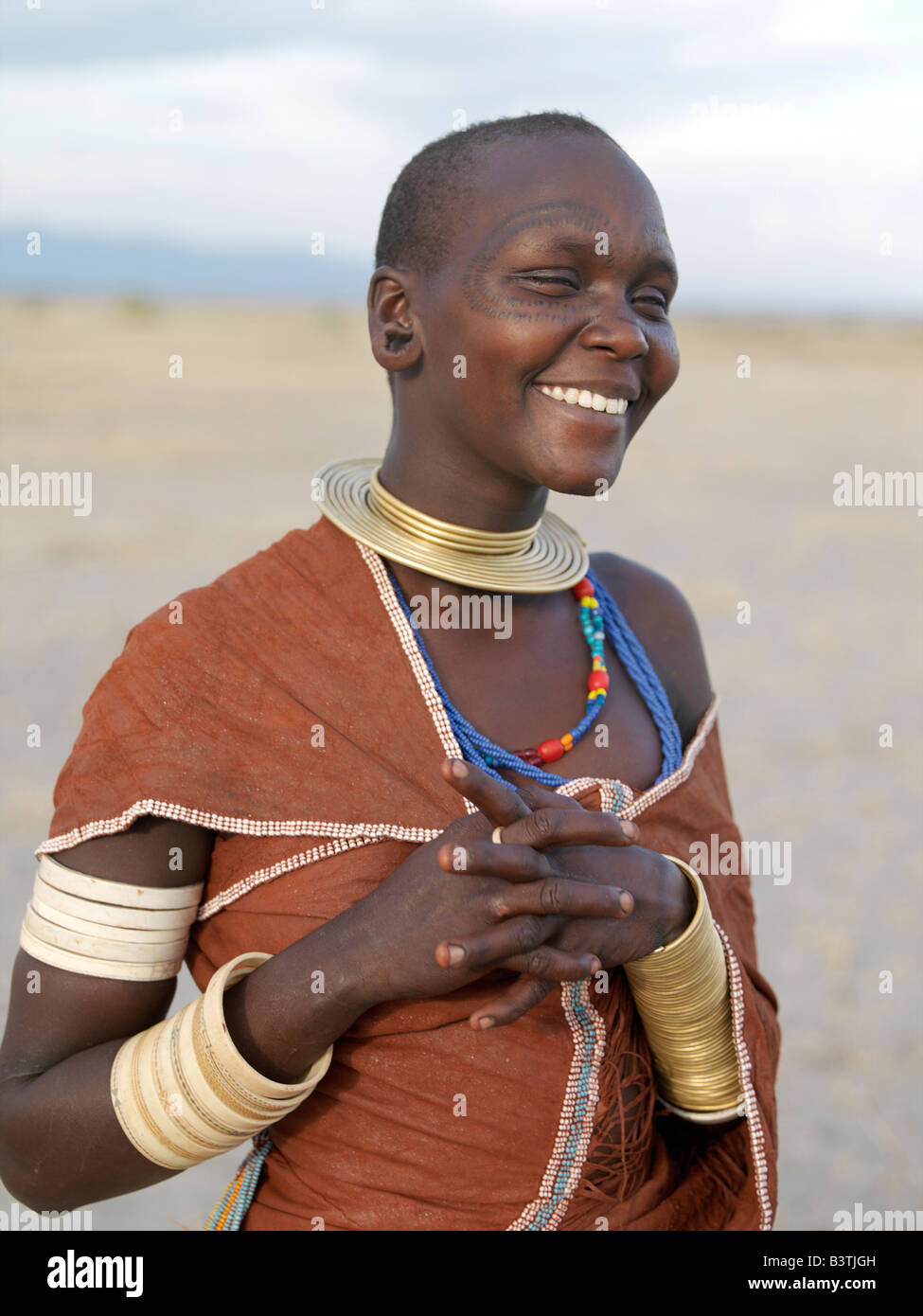 Tanzania, Northern Tanzania, Manyara. A Datoga woman in jovial mood. The traditional attire of Datoga women includes beautifully tanned and decorated leather dresses and coiled brass armulets and necklaces. Yellow and light blue are the preferred colours of the beads they wear. Scarification of the face is not uncommon among women and girls.The Datoga (known to their Maasai neighbours as the Mang'ati and to the Iraqw as Babaraig) live in northern Tanzania and are primarily pastoralists. Stock Photo