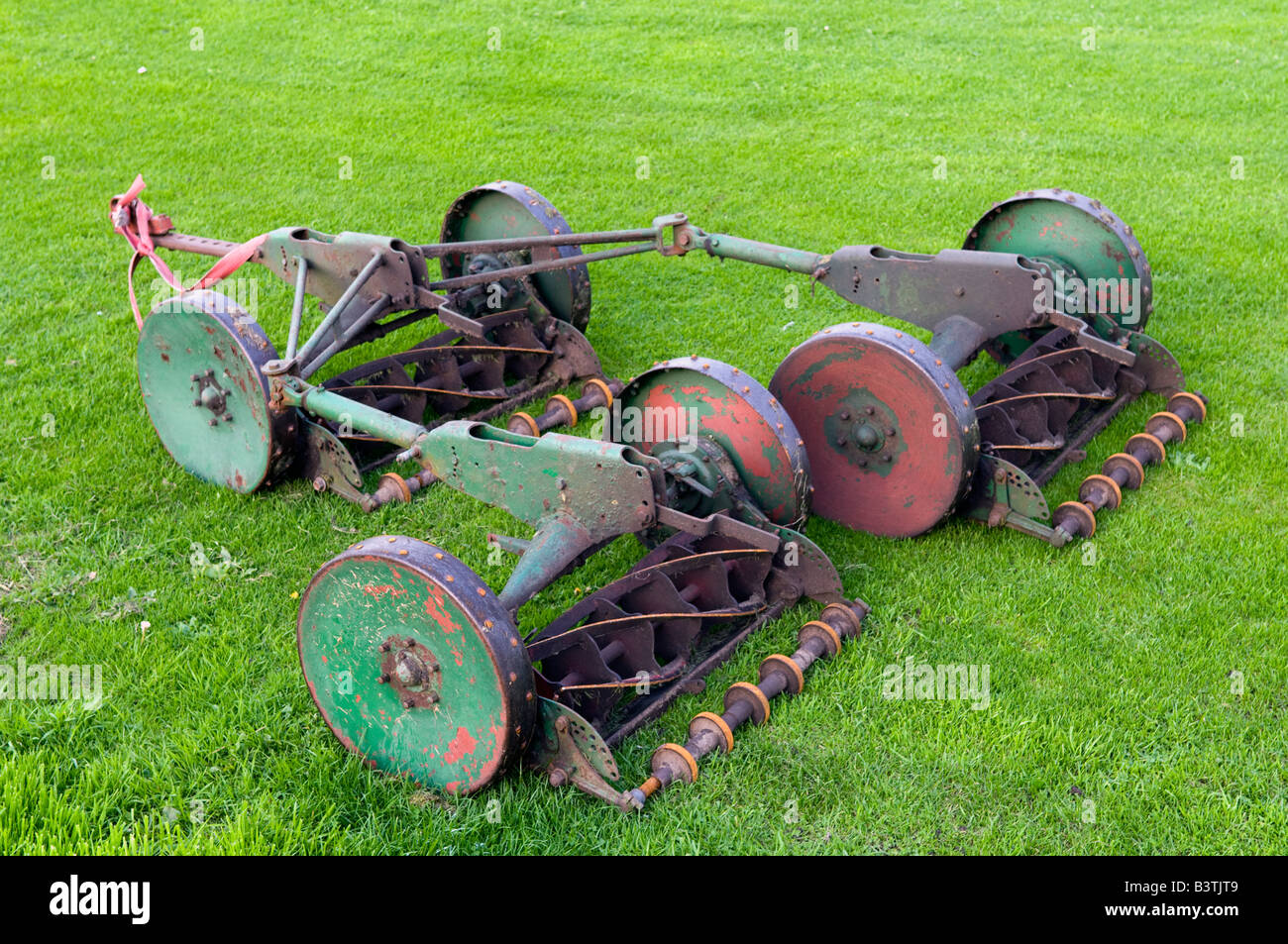 Towable triple cutting lawnmower on the edge of a green lawn Stock Photo