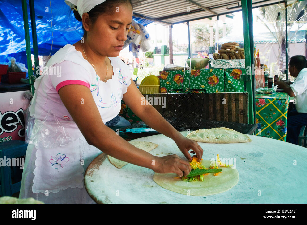 woman is making tortillas tortillas with flor de calabaza at a stall in