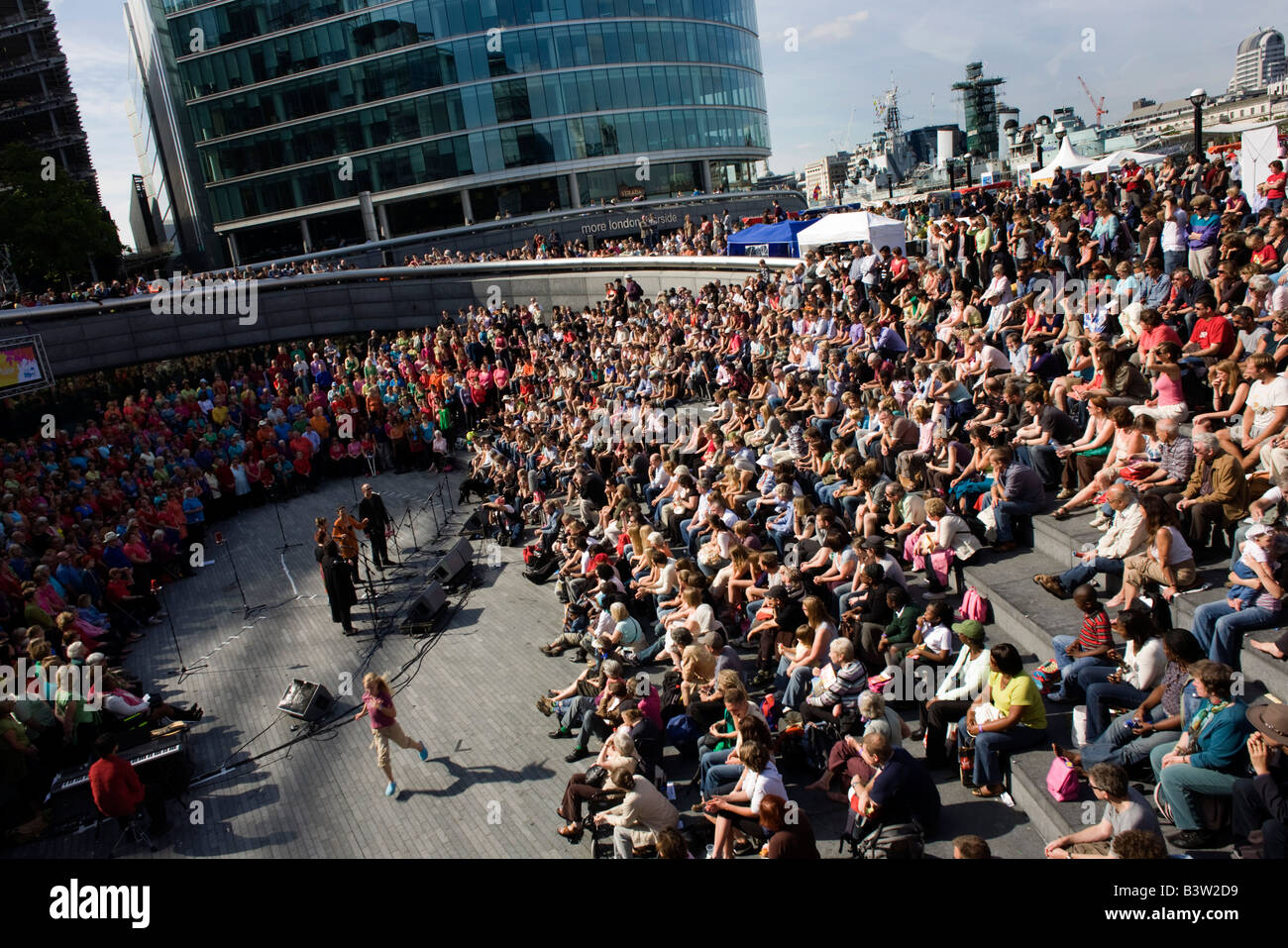 Audience listens to songs for Wateraid by multinational 1000-voice choir at The Scoop during London's Thames Festival Stock Photo