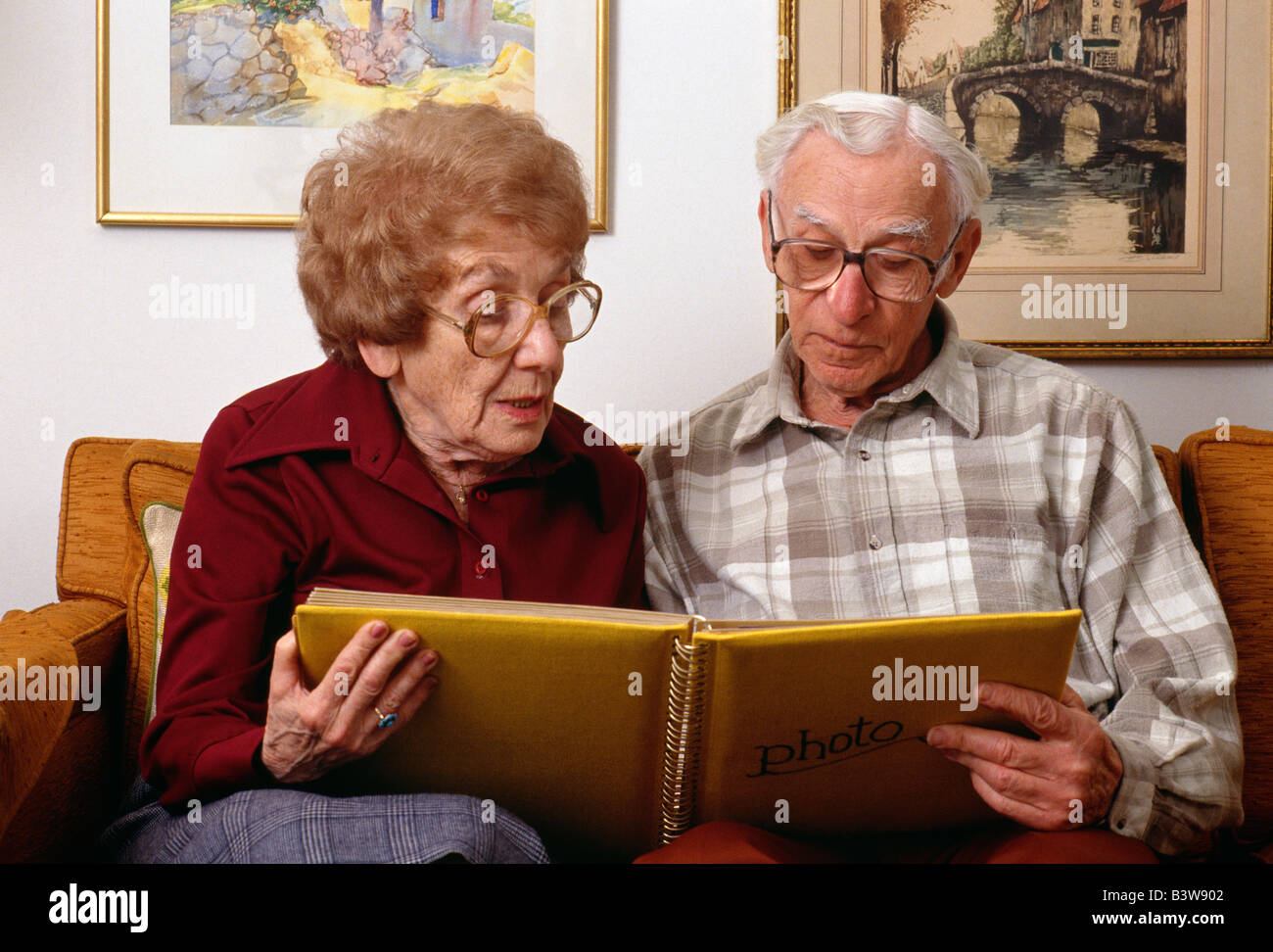Elderly couple looking at a photo album in their home Stock Photo - Alamy