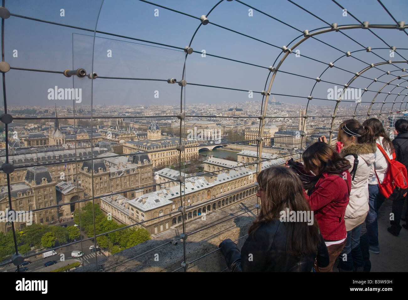 Young french girls and tourists admire the scenic panorama of Paris from the Chimera Gallery of Notre Dame Cathedral Paris Franc Stock Photo
