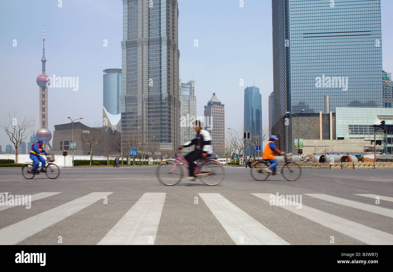 People cycling on street. Oriental Pearl Tower, Jin Mao Tower and the Shanghai World Financial Center. Pudong, Shanghai, China Stock Photo