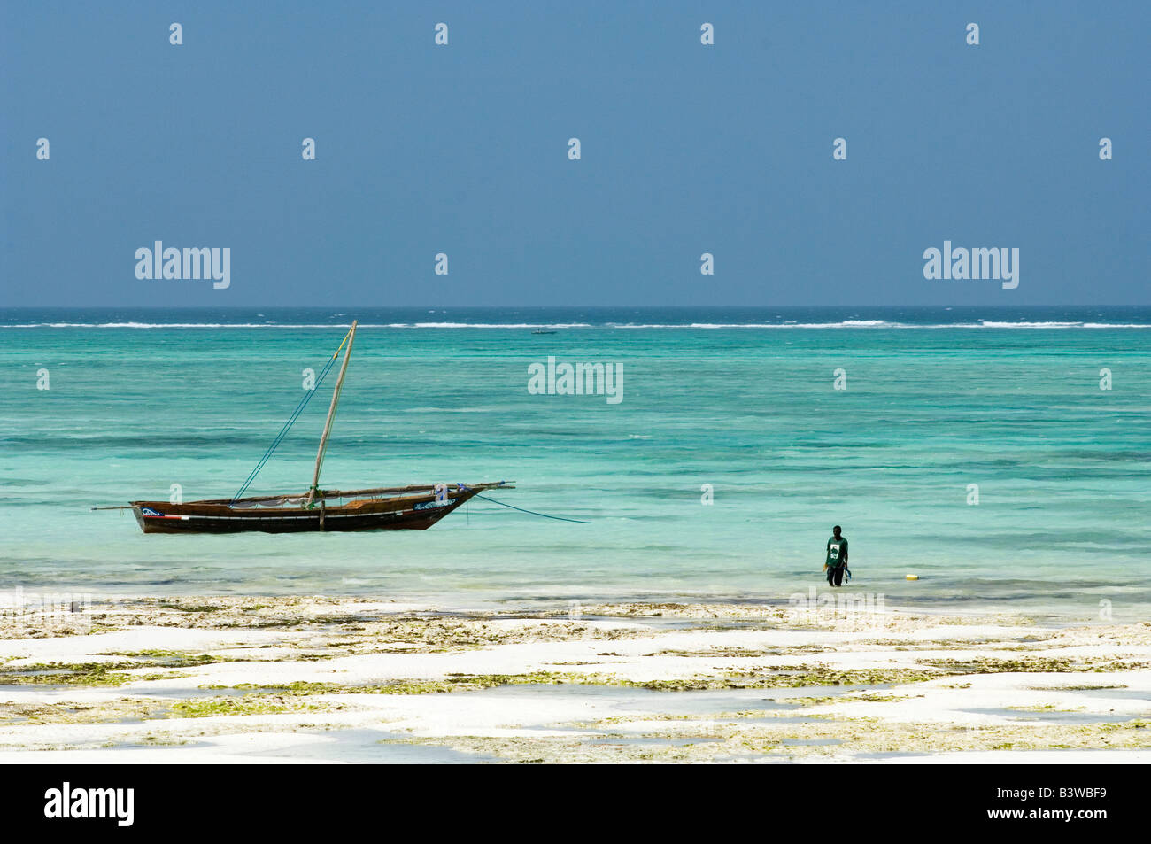 Fisherman anchoring his boat in a lagoon in Nungwi, Zanzibar, Tanzania Stock Photo
