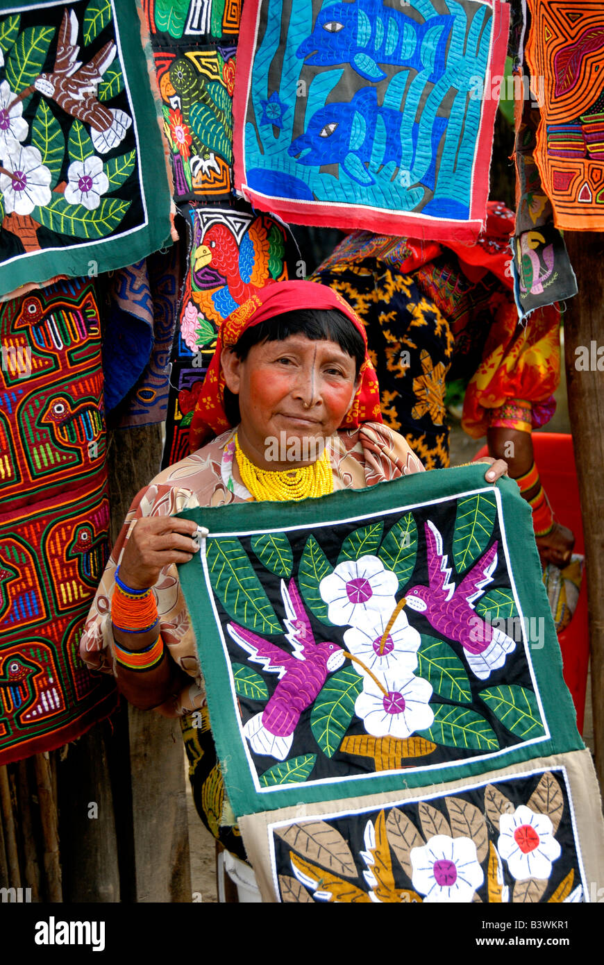 Central America, Panama, San Blas Islands. Kuna Indian woman in traditional attire in front of colorful hand stitched molas. Stock Photo