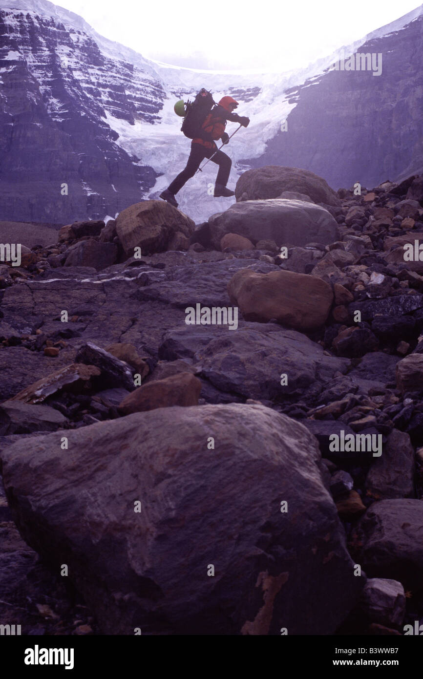 Side profile of a mountaineer jumping from rock to rock, Alberta, Canada Stock Photo