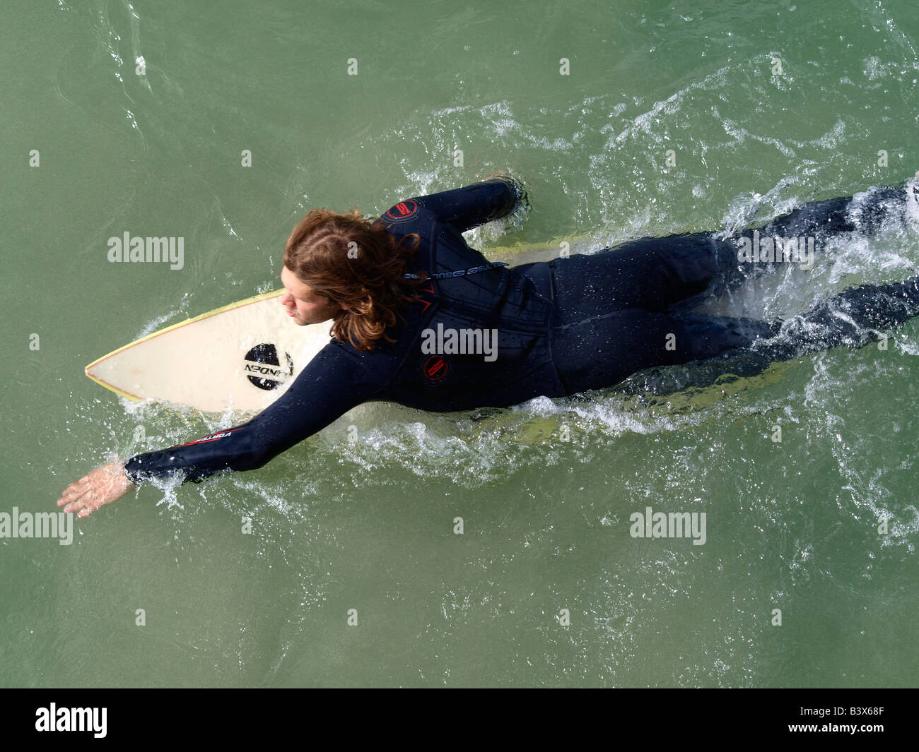 Surfer Lying Flat On His Surfboard Paddling Out Towards The Surfer Lying Flat On His Surfboard Paddling Out Towards The