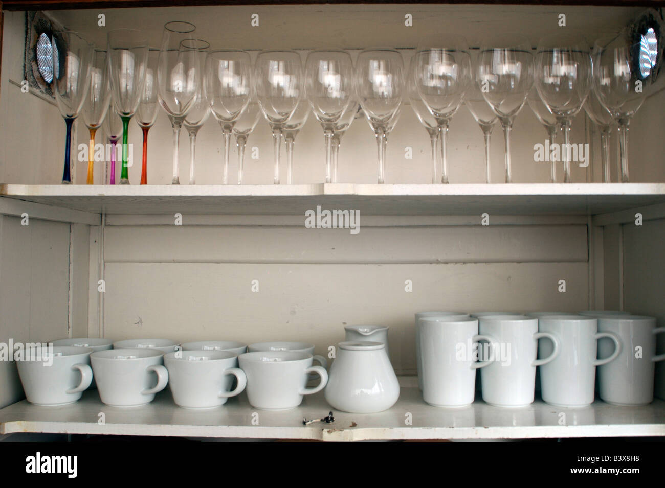 Antique cupboard with contemporary dinnerware and stemware Stock Photo