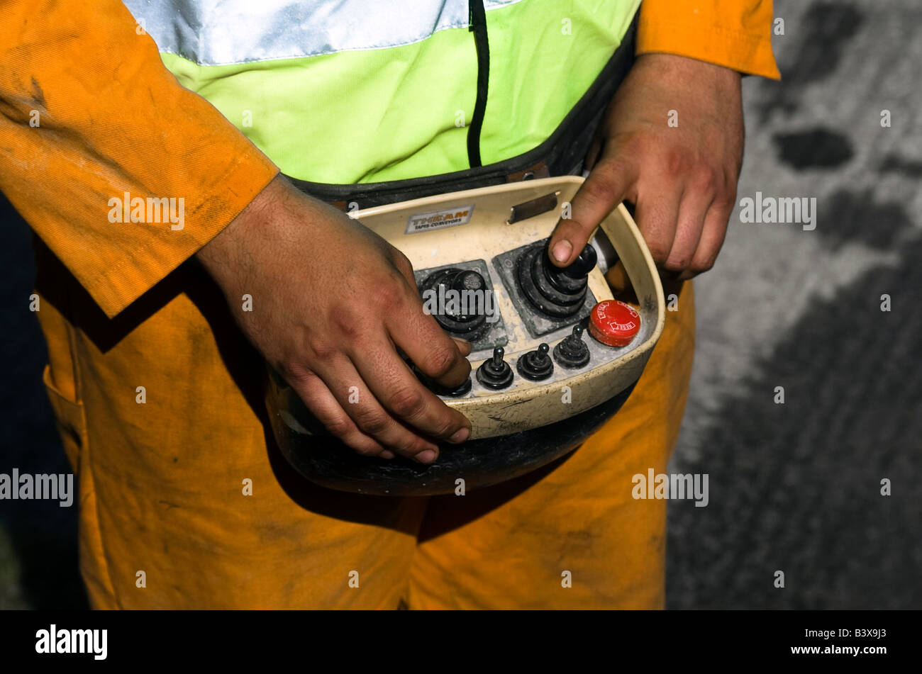 A workman is operating the concrete cement mixer remotely by pushing the buttons on his remote system Stock Photo