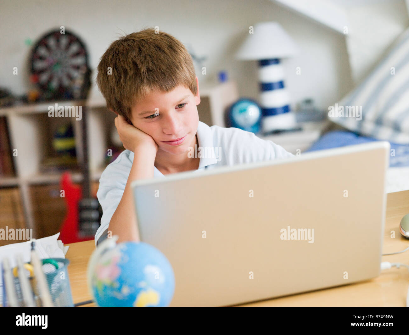 Young Boy Using A Laptop In His Bedroom Stock Photo - Alamy
