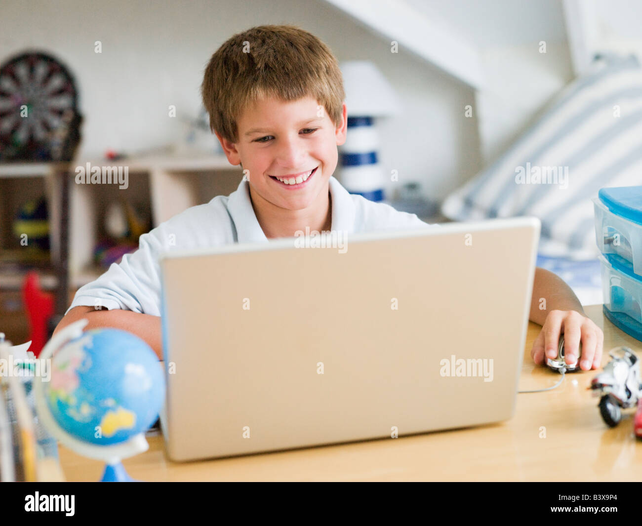 Young Boy Using A Laptop In His Bedroom Stock Photo - Alamy