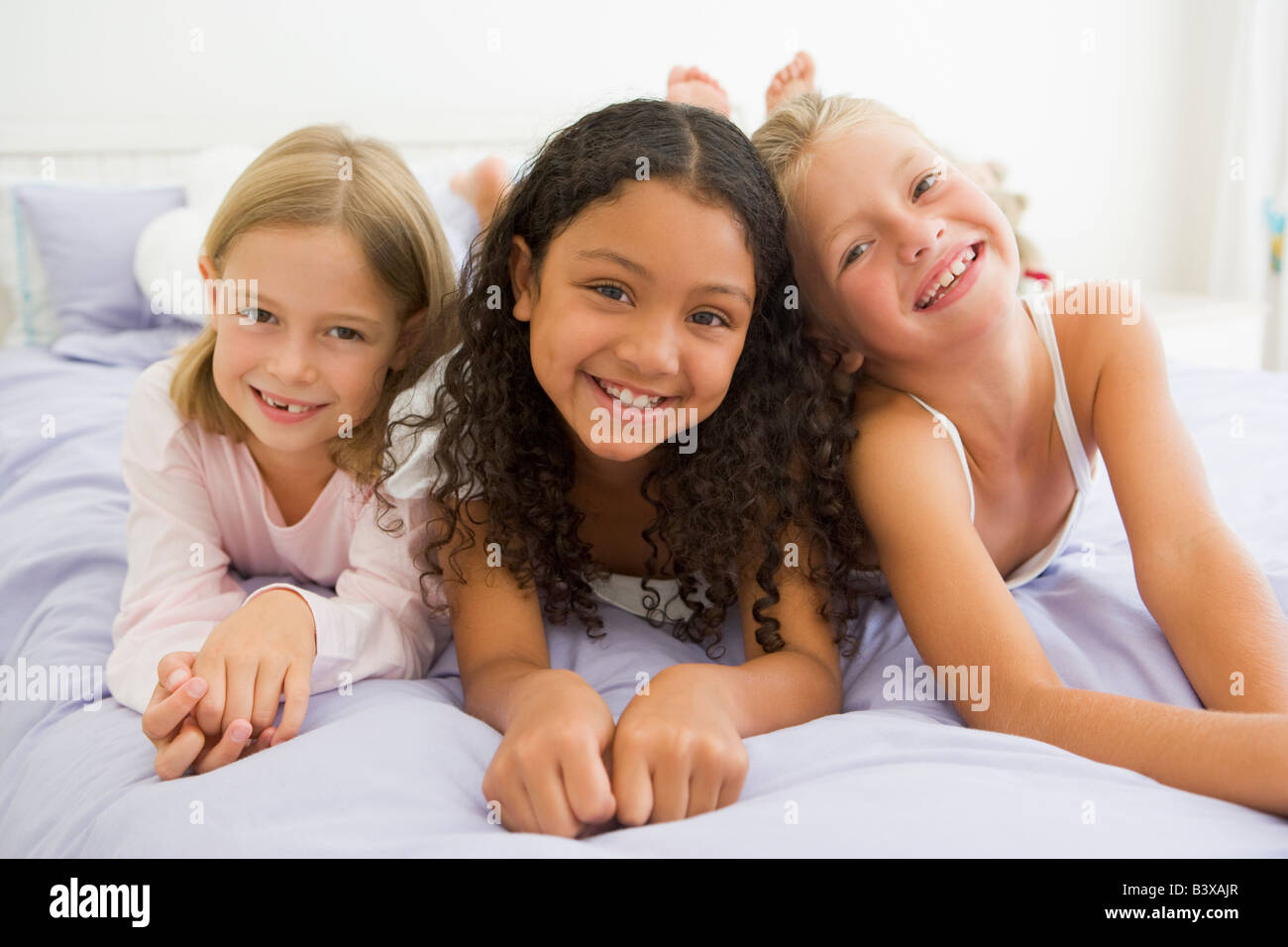 Three Young Girls Lying On A Bed In Their Pajamas Stock Photo - Alamy