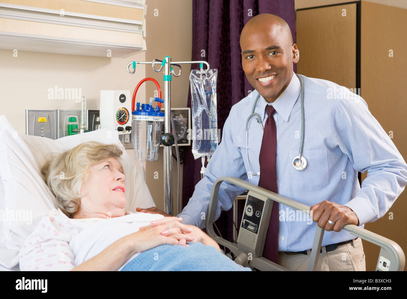 Doctor Checking Up On Patient Lying In Hospital Bed Stock Photo