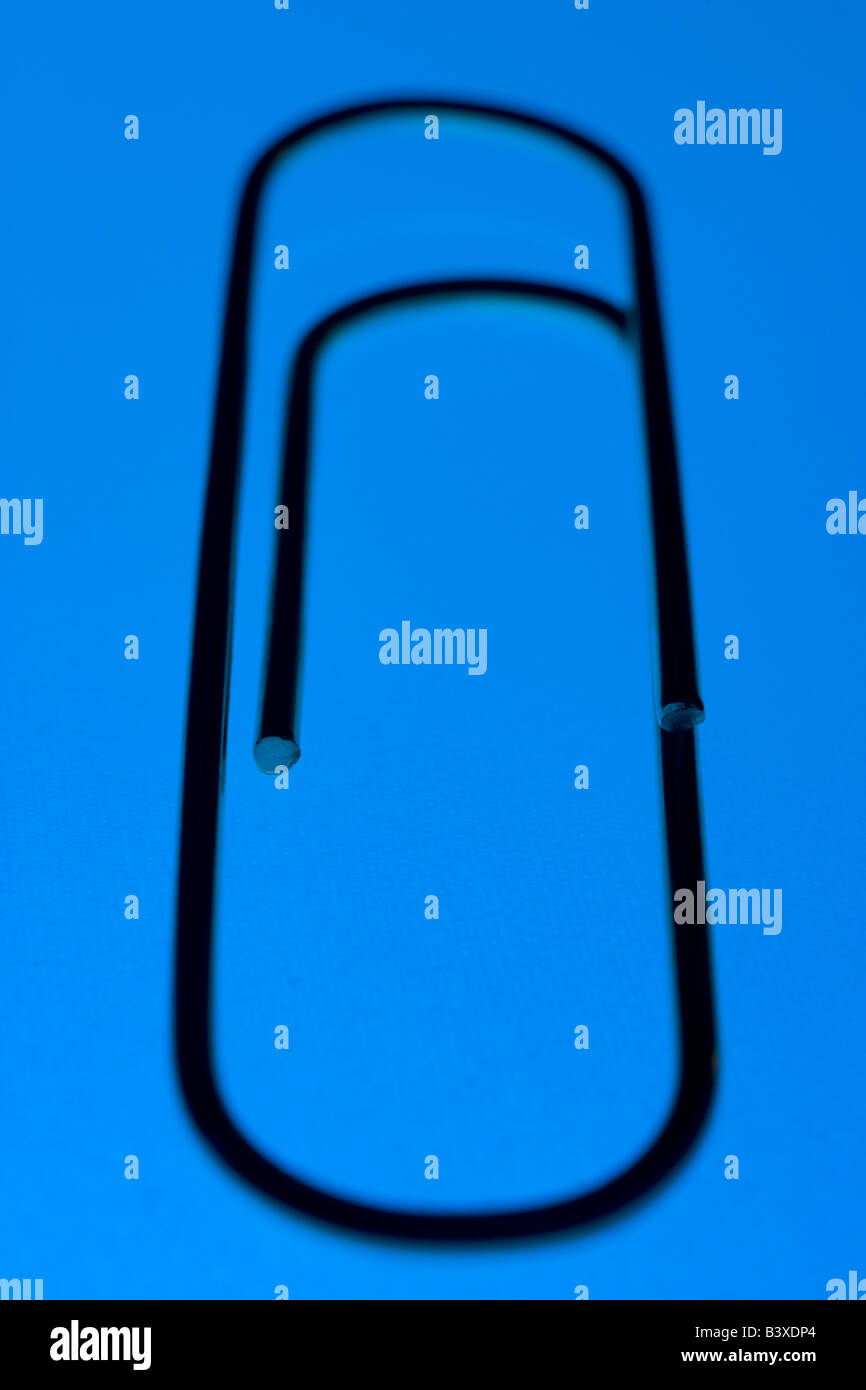 Close Up Of A Blue Paperclip, Against A Blue Background Stock Photo