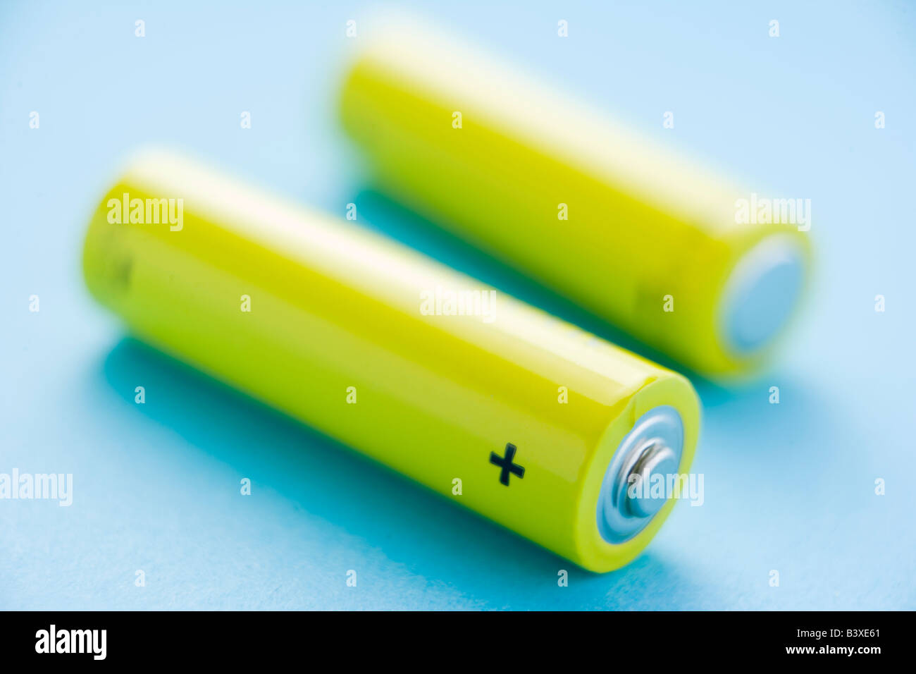 Two Yellow Batteries Against A Blue Background Stock Photo