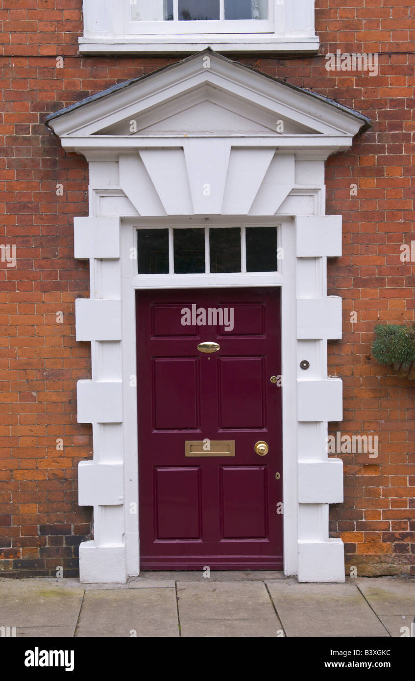 Maroon front door with glazed skylight and triangular pediment of
