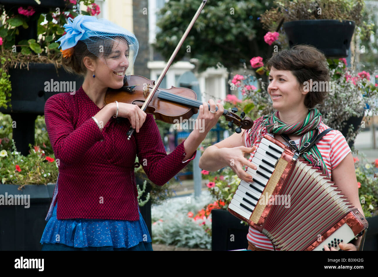 Two young women busking in the street in Aberystwyth Wales UK playing violin and accordion squeeze box Stock Photo