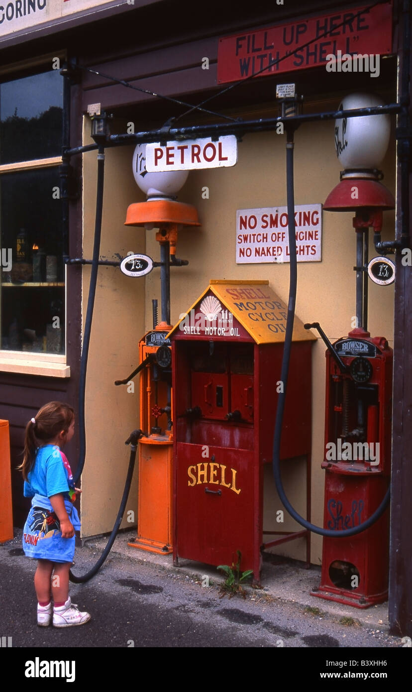 Small girl looks at an old fashioned Shell petrol pump system at Amberley Industrial Museum, Sussex, UK. Stock Photo