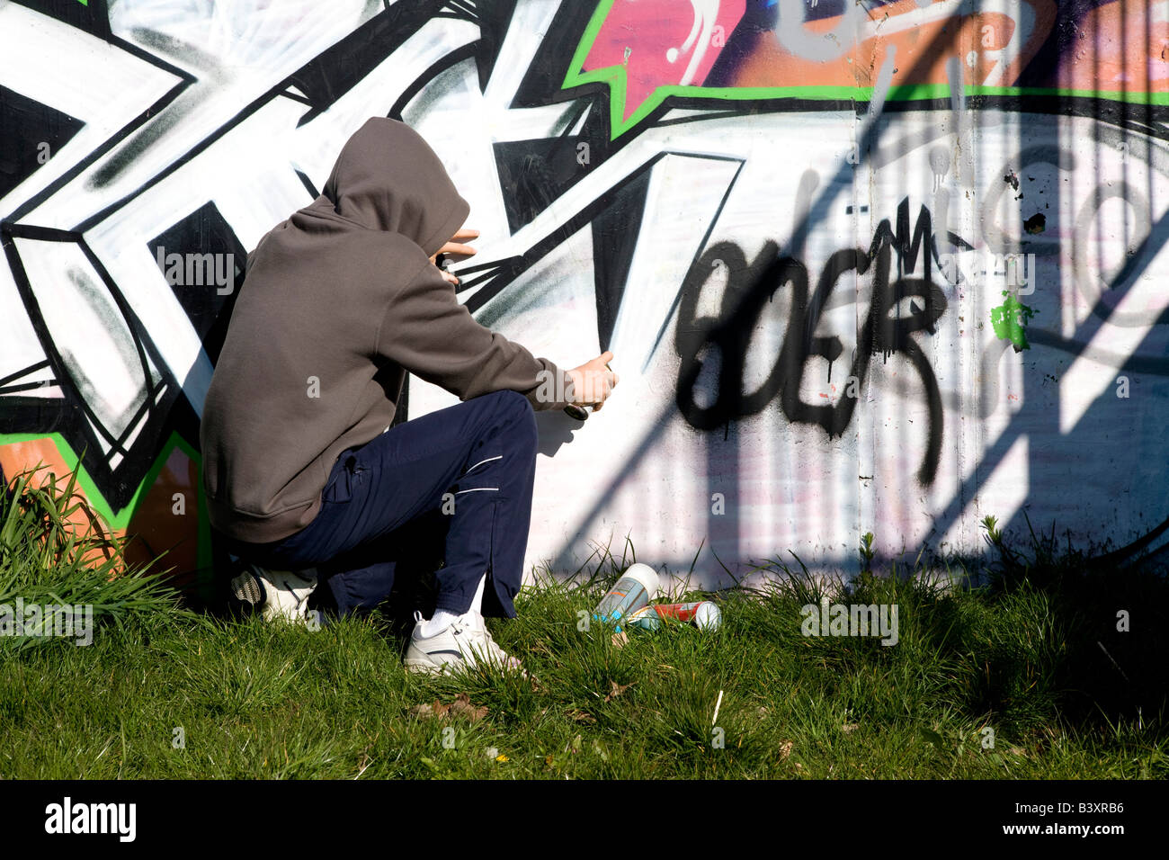 youth spraying graffiti on wall Stock Photo