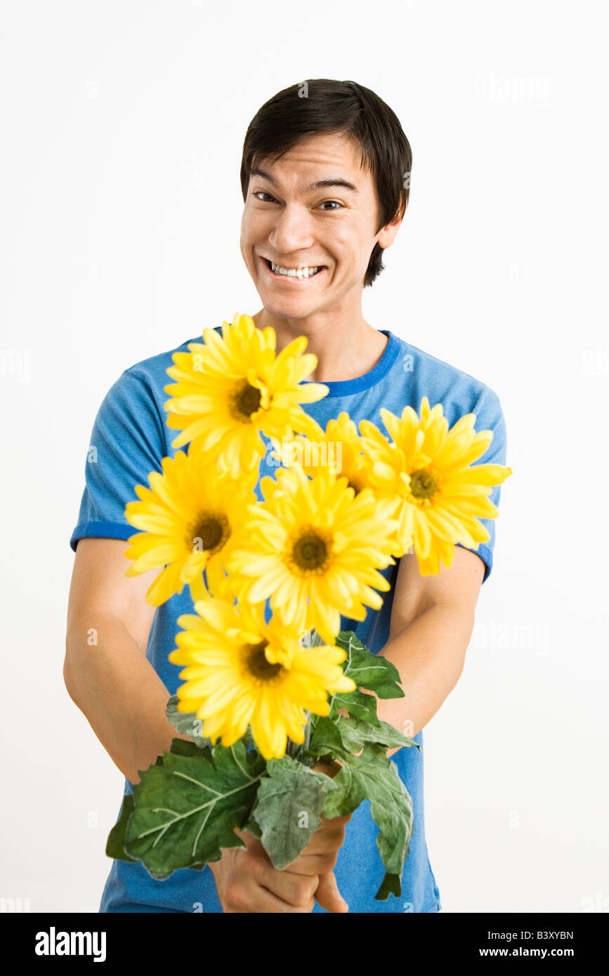 Asian young man holding bouquet of yellow gerber daisies smiling Stock Photo