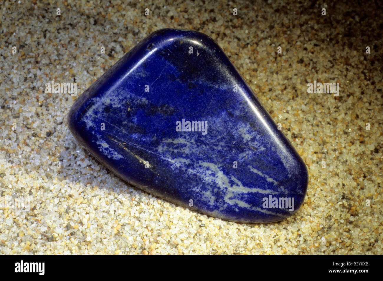Lapis Lazuli, polished pebble on sand Stock Photo