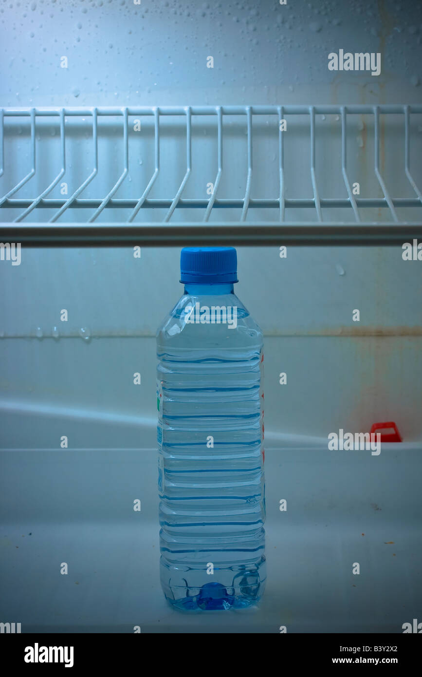 Unopened plastic water bottle in a dirty fridge. Stock Photo