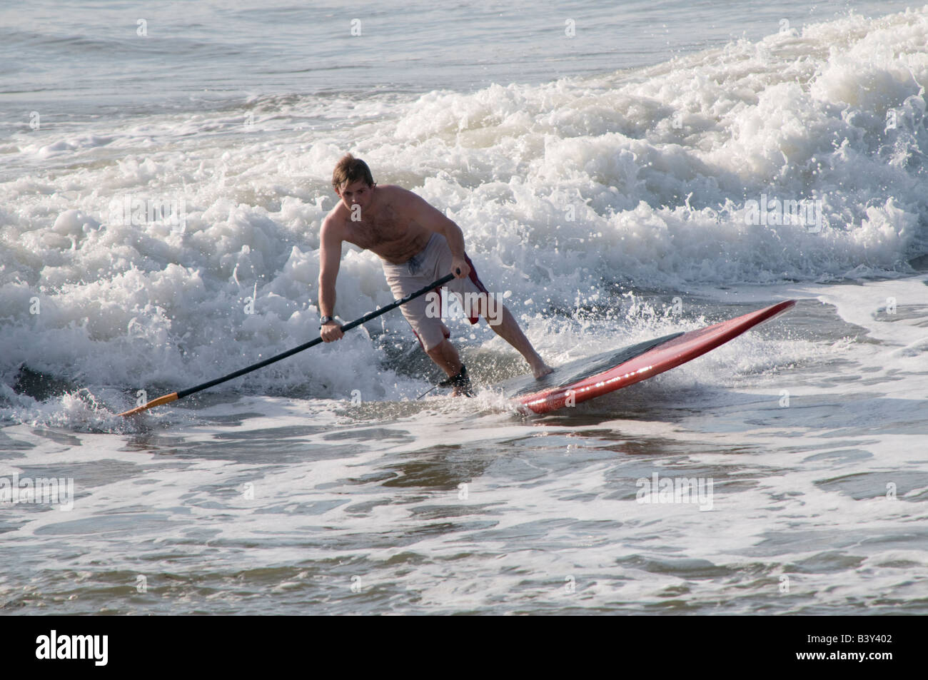 Young teenage boy surfing on the waves off Aberystwyth - stand up surf paddling on a board Stock Photo