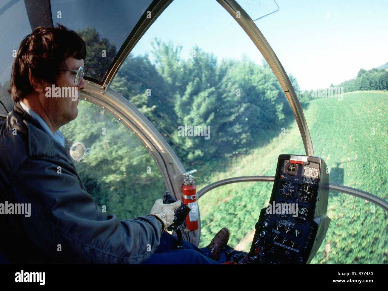 Helicopter crop dusting hilly terrain at low altitude in western Pennsylvania, USA Stock Photo
