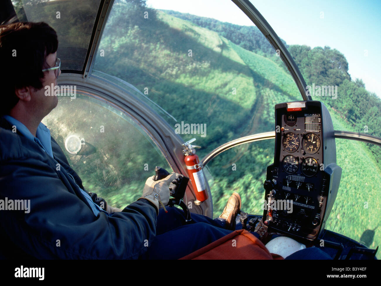 Helicopter crop dusting hilly terrain at low altitude in western Pennsylvania, USA Stock Photo