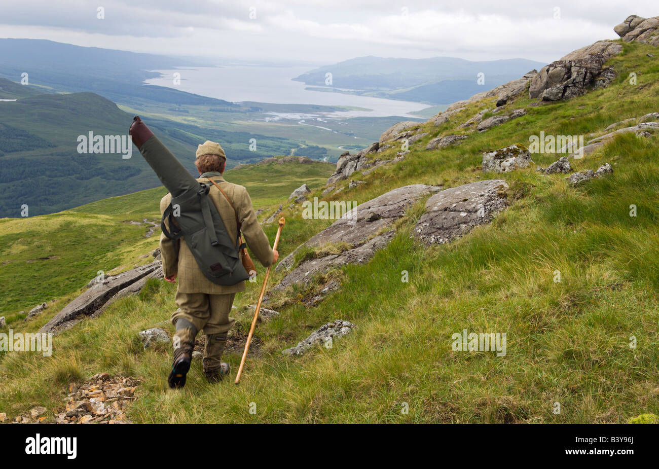 Scotland, Hebrides, Mull. Benmore Estate stalker, Neilson Bissett, on the hill stalking red deer. He carries binoculars, telescope, stalking rifle and walking stick. Stock Photo