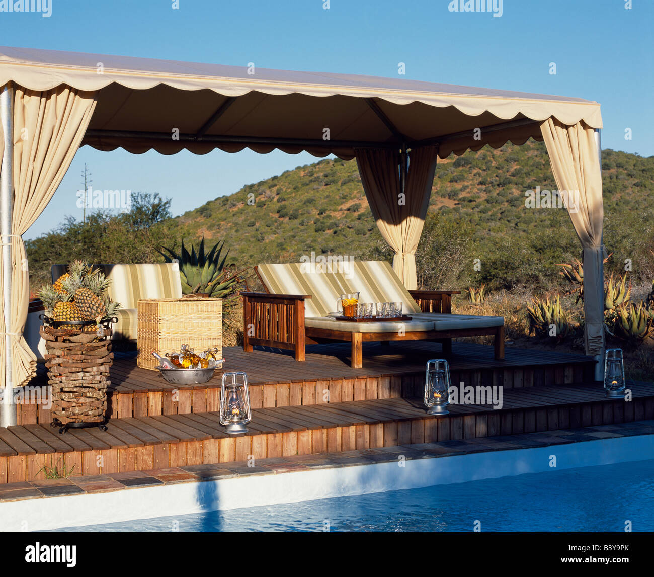South Africa, Eastern Cape, Kwandwe . Sun loungers on a canopied deck beside the swimming pool