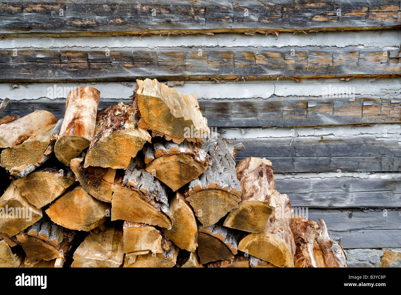 Cord wood stacked next to old log cabin Nevada City Montana Stock Photo