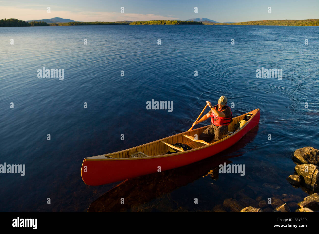 A man paddles his canoe on Seboeis Lake near Millinocket, Maine. Mount
