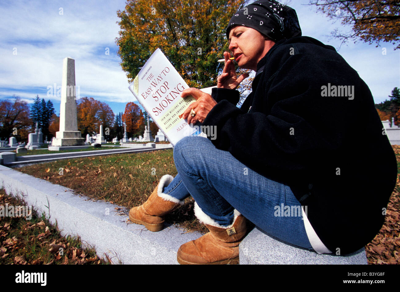North America, United States, New England. Woman with a self help book at a cemetery. Stock Photo