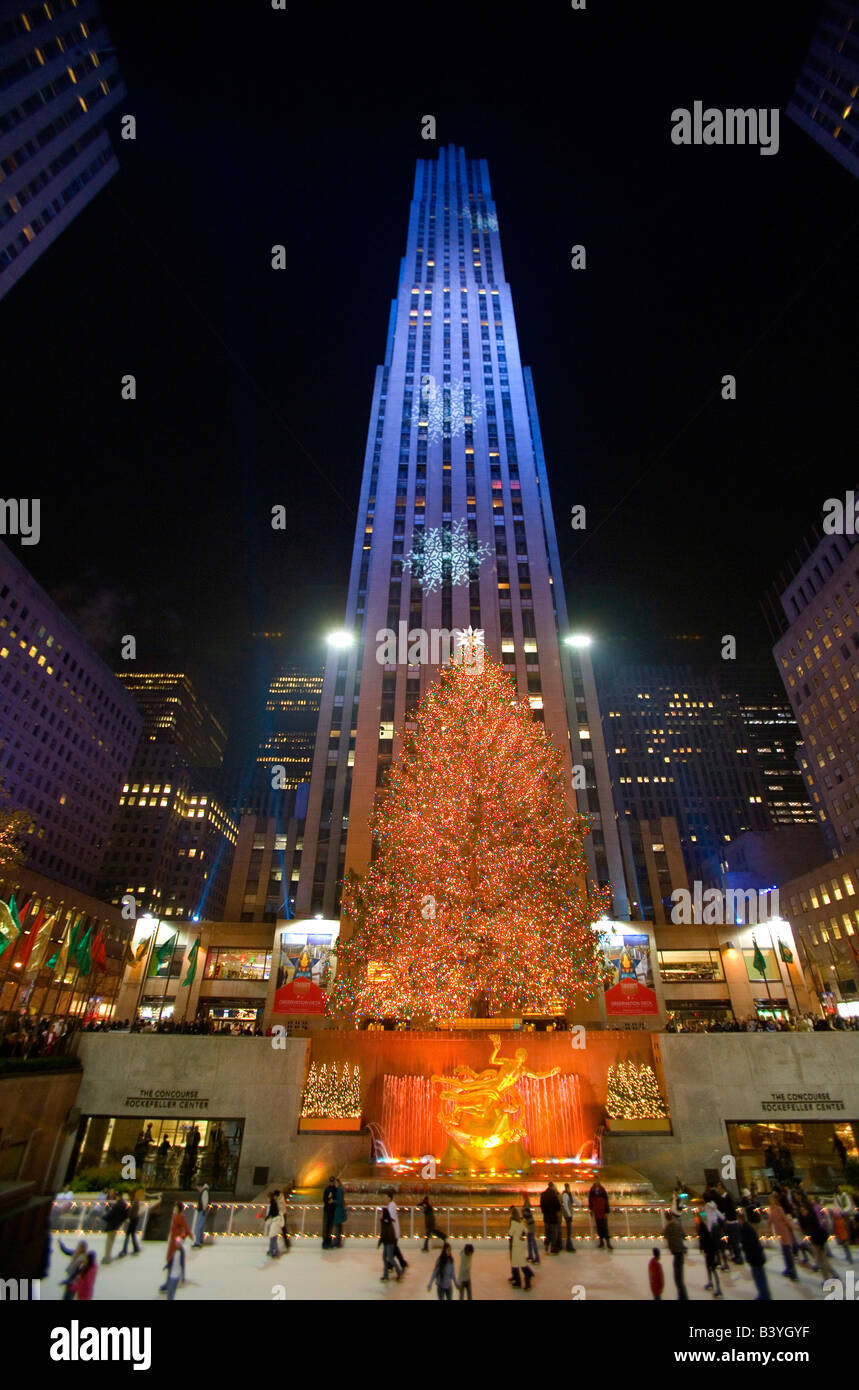 Skaters at Rockefeller Center Ice Rink, Christmas Tree and projected Snow Flakes on illuminated buildings. Stock Photo