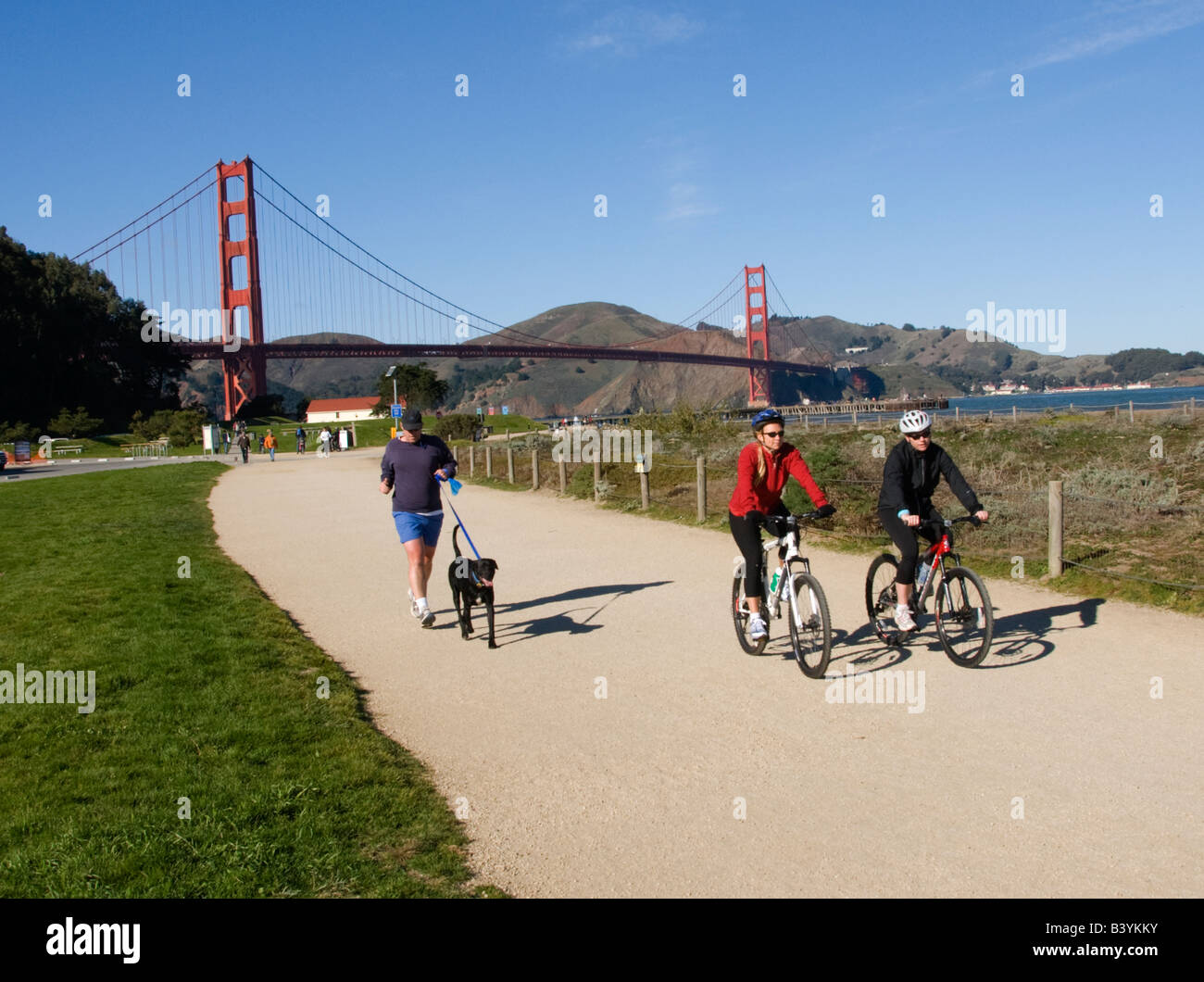 Bicyclists and dog walkers enjoy Crissy Field near the Golden Gate Bridge in San Francisco CA California Stock Photo
