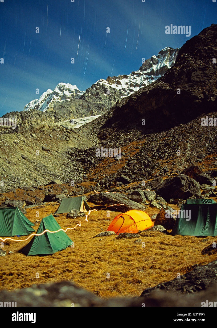 Nepal, Solo-Khumbu, Khare (Mera Peak Basecamp). Nighttime shot of tents at Mera Base Camp at Khare (5000m). Star trails are visable in the sky as is the path of a torch held by a camper. Stock Photo