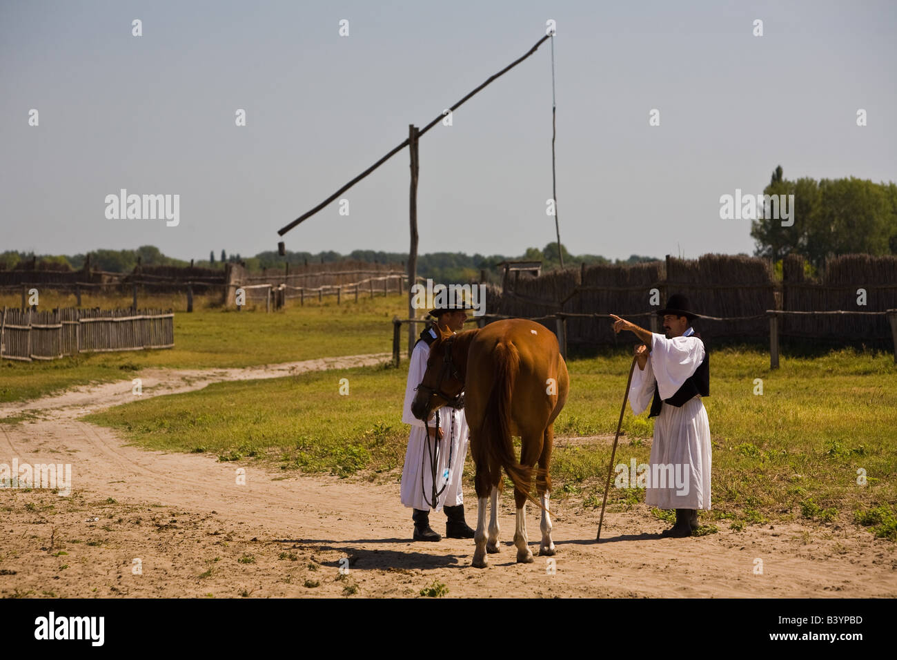 Two shepherds in front of a draw well in the Puszta of Bugac which is ...