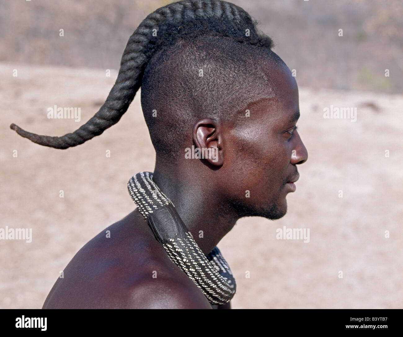 Namibia, Kaokoland, Epupa. A Himba youth has his hair ...