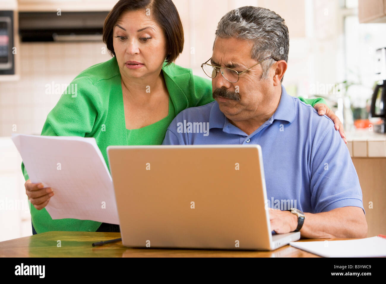 Couple in kitchen with laptop and paperwork Stock Photo - Alamy