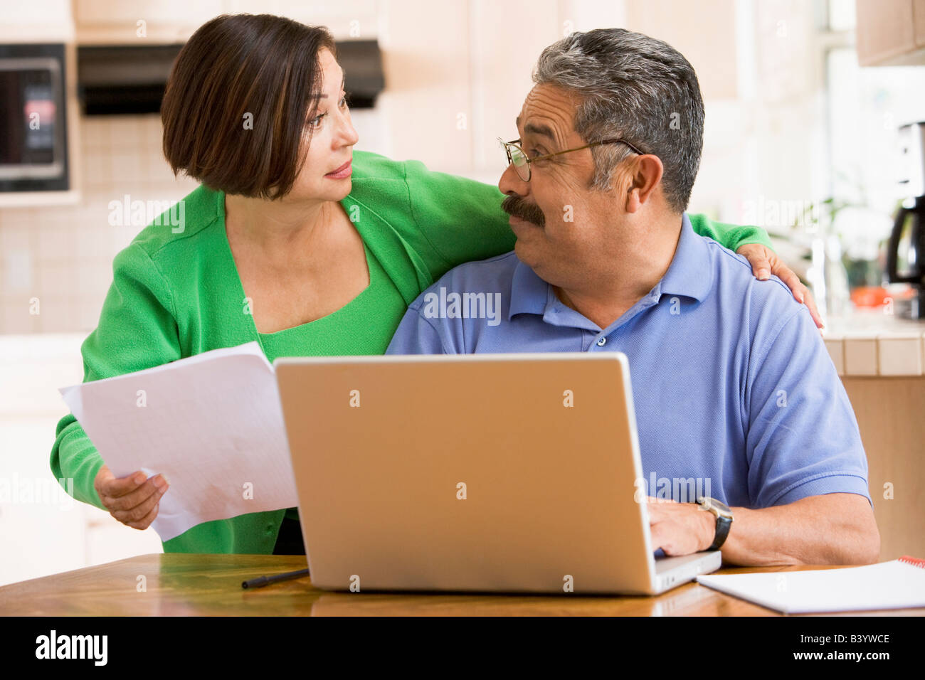 Couple in kitchen with laptop and paperwork Stock Photo - Alamy
