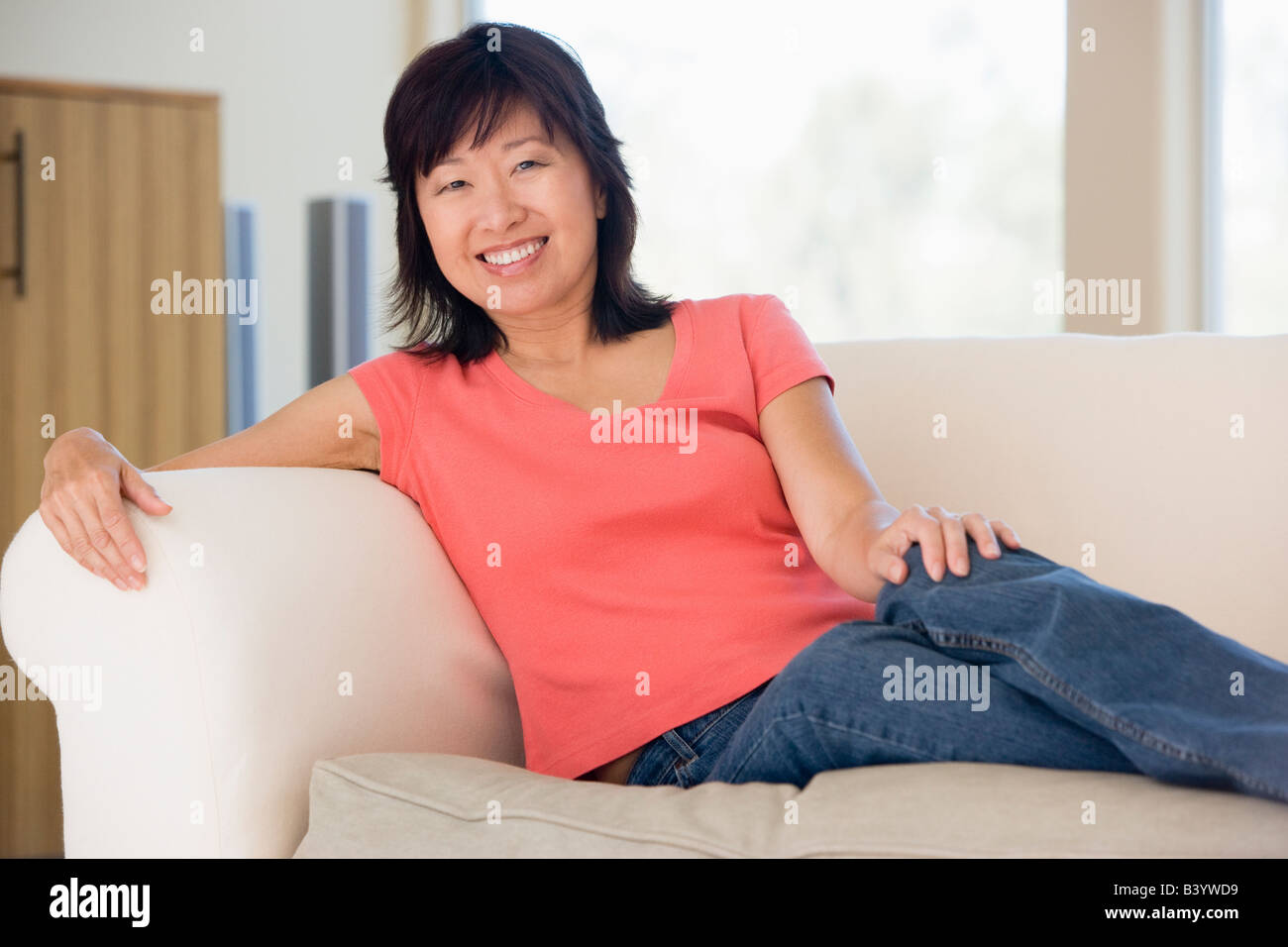 Woman relaxing in living room smiling Stock Photo - Alamy