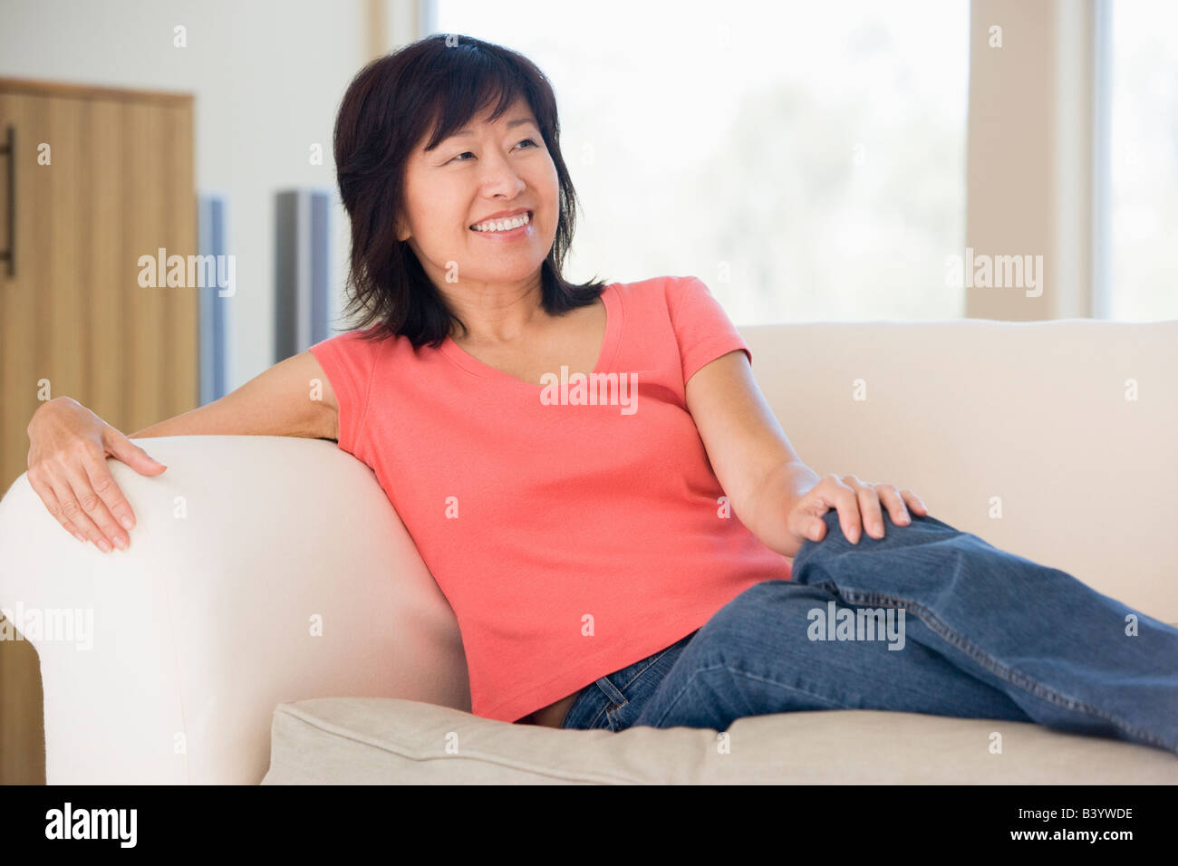 Woman relaxing in living room smiling Stock Photo - Alamy