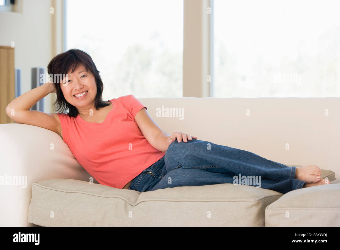 Woman relaxing in living room smiling Stock Photo - Alamy