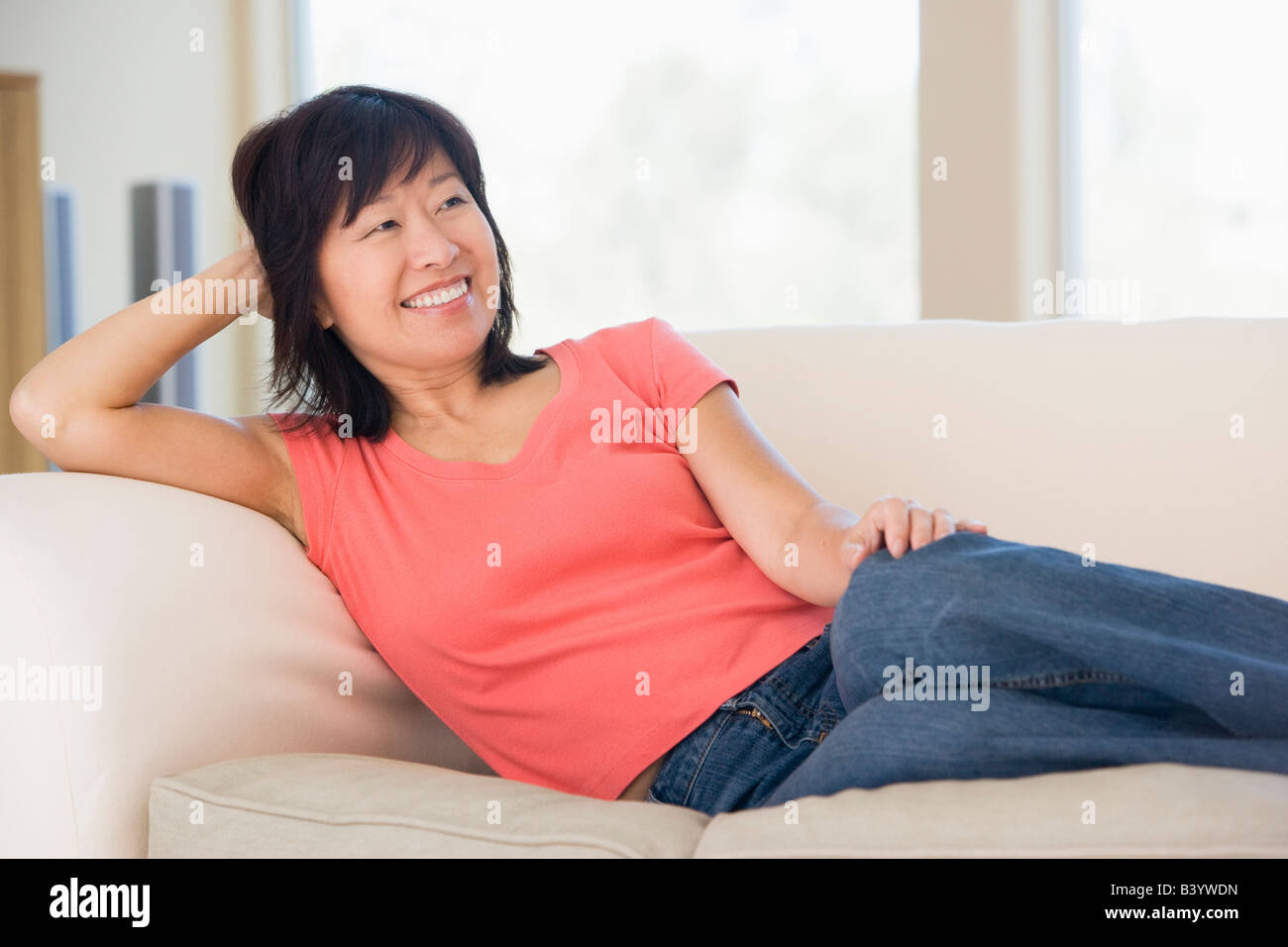 Woman relaxing in living room smiling Stock Photo - Alamy