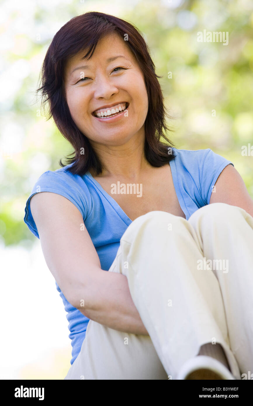 Woman sitting outdoors smiling Stock Photo - Alamy