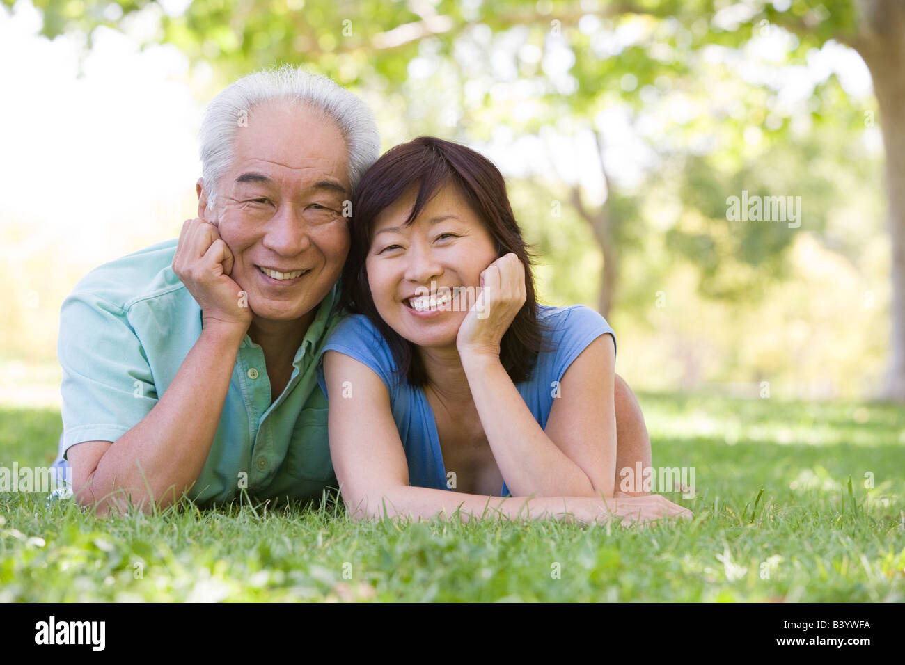 Couple relaxing outdoors in park smiling Stock Photo - Alamy