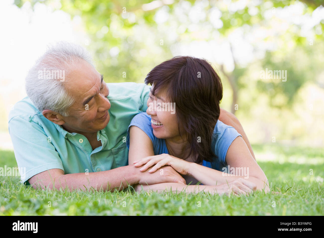 Couple relaxing outdoors in park smiling Stock Photo - Alamy
