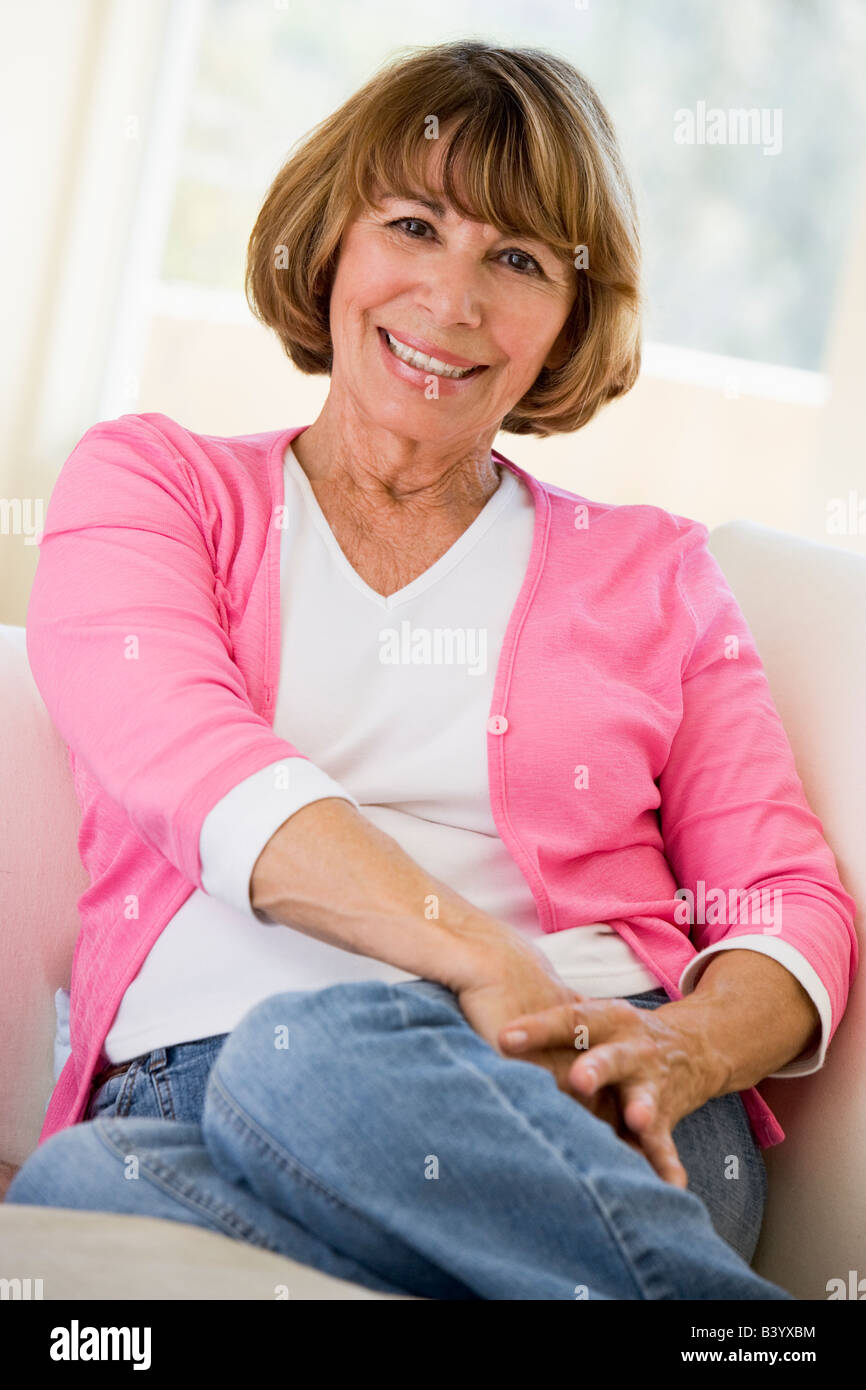 Woman sitting in living room smiling Stock Photo - Alamy